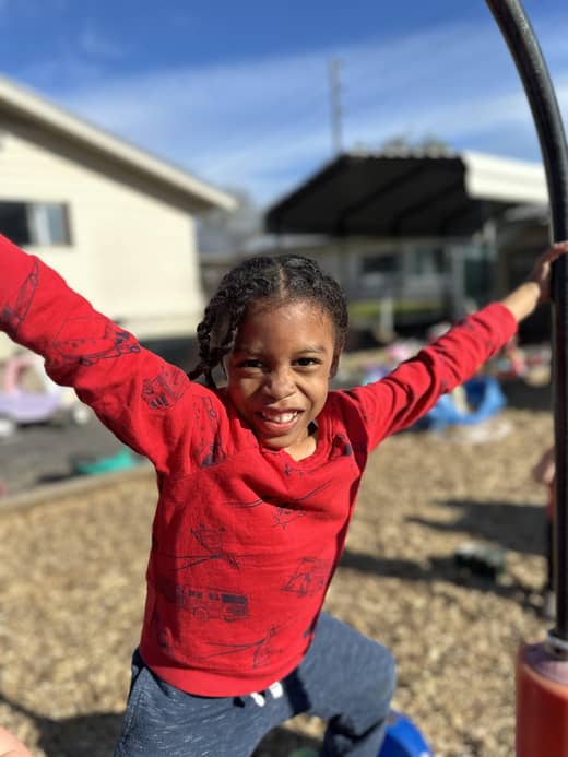 Smiling child playing outdoors at Lil’ Patriots Academy childcare center Puyallup, supporting growth through active preschool programs.