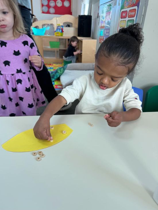 Child working on a hands-on cooking project with cereal pieces at Lil’ Patriots Academy, part of the preschool and early education program in Puyallup.
