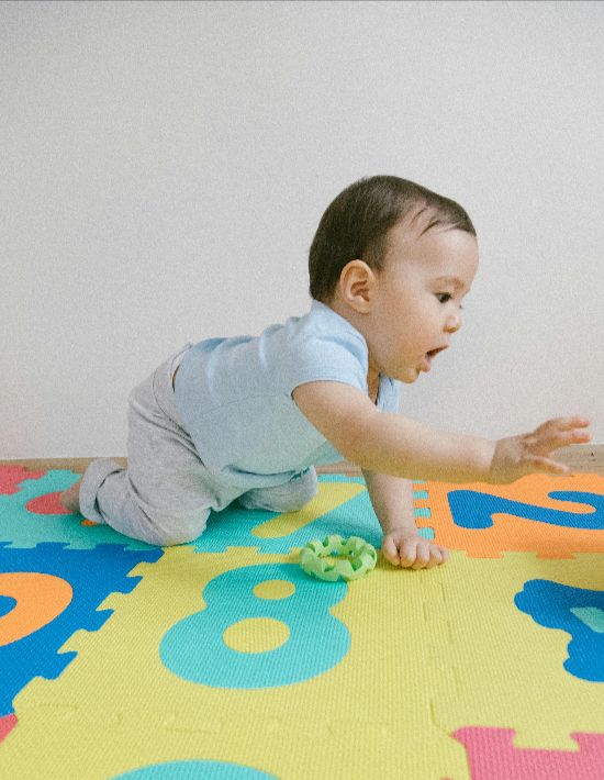 Baby playing on colorful mats at Lil’ Patriots Academy infant program, where infant sign language and early development are encouraged.