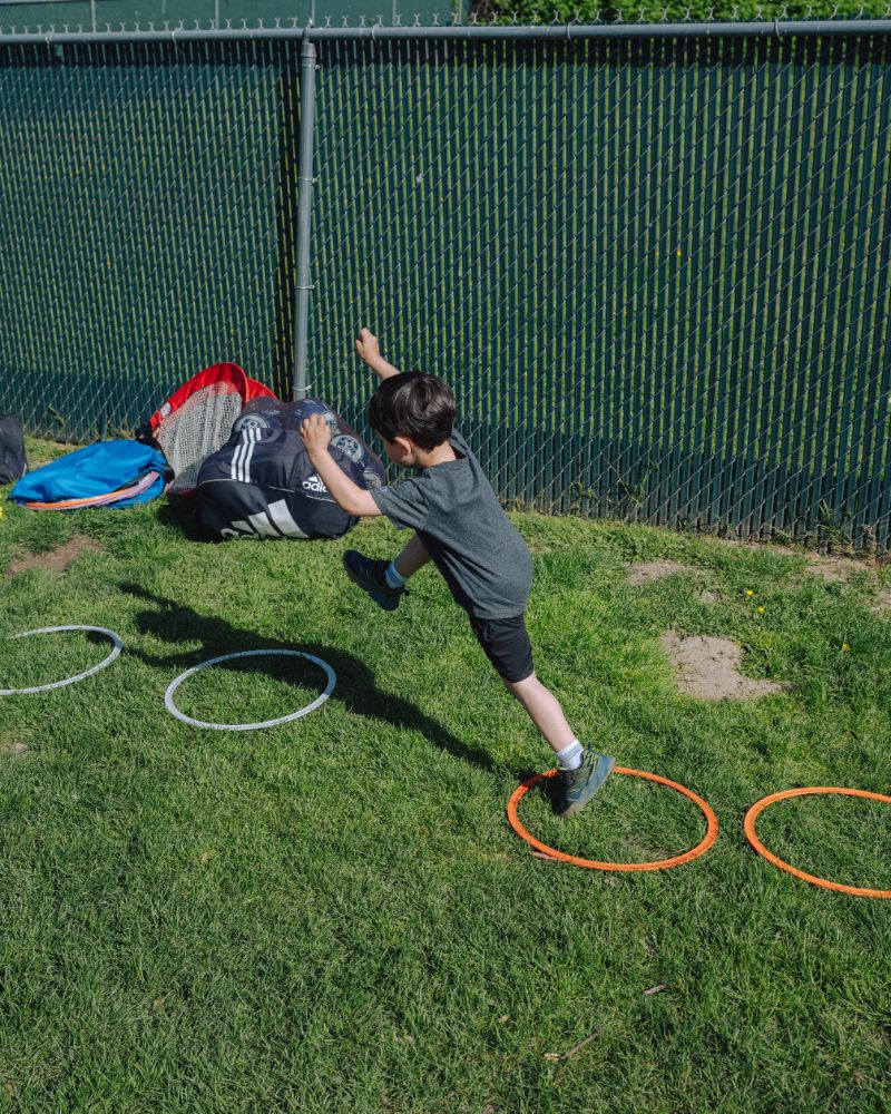 Child jumping through hoops in the outdoor play area at Lil’ Patriots Academy, part of the advanced preschool curriculum.