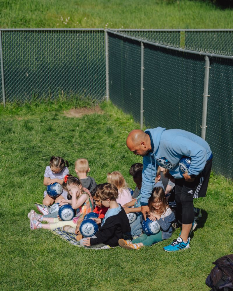 Instructor guiding children with balls during outdoor learning at Lil’ Patriots Academy, part of the ASL preschool program in Puyallup.