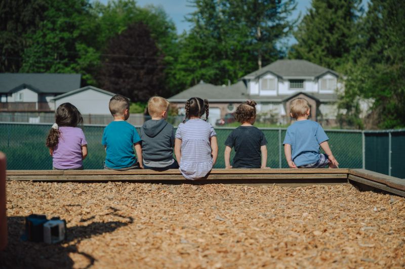 Group of preschoolers sitting together outdoors at Lil’ Patriots Academy, highlighting the Pre-K alternative and social learning in Puyallup.