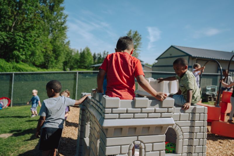 Preschool children playing together on outdoor playground equipment at Lil’ Patriots Academy, supporting pre-k learning and social development.