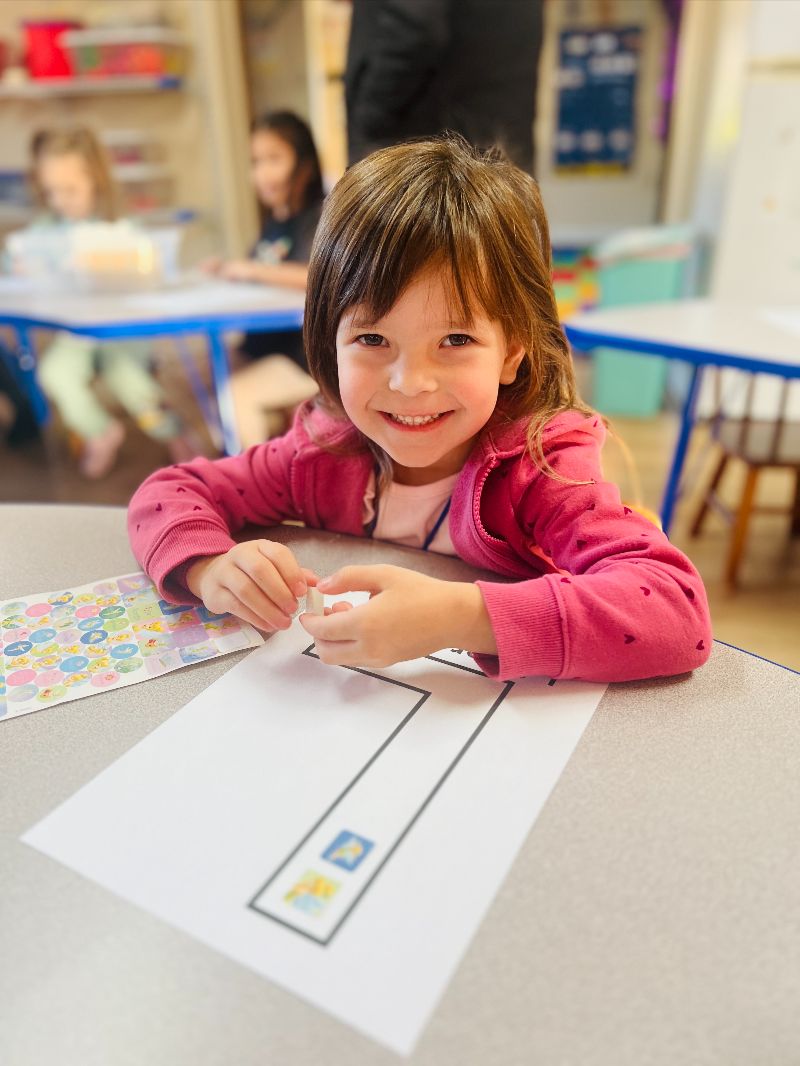 Smiling Pre-K student participating in a hands-on activity at Lil’ Patriots Academy in Puyallup, promoting kindergarten readiness and early education.