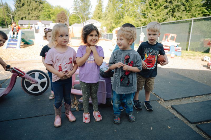 Toddlers and preschoolers smiling and playing together outdoors at Lil’ Patriots Academy Puyallup, showcasing the Abeka and HighScope play-based curriculum.
