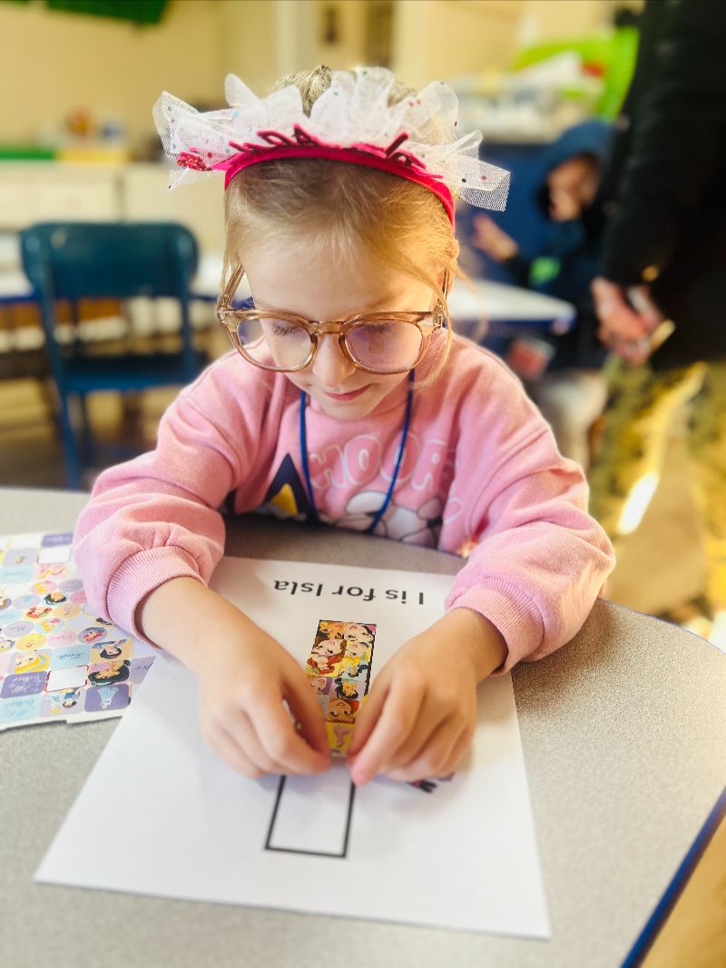 Young girl doing a fun art and sticker activity at a daycare in Puyallup WA, promoting creativity and fine motor skills in early learning.