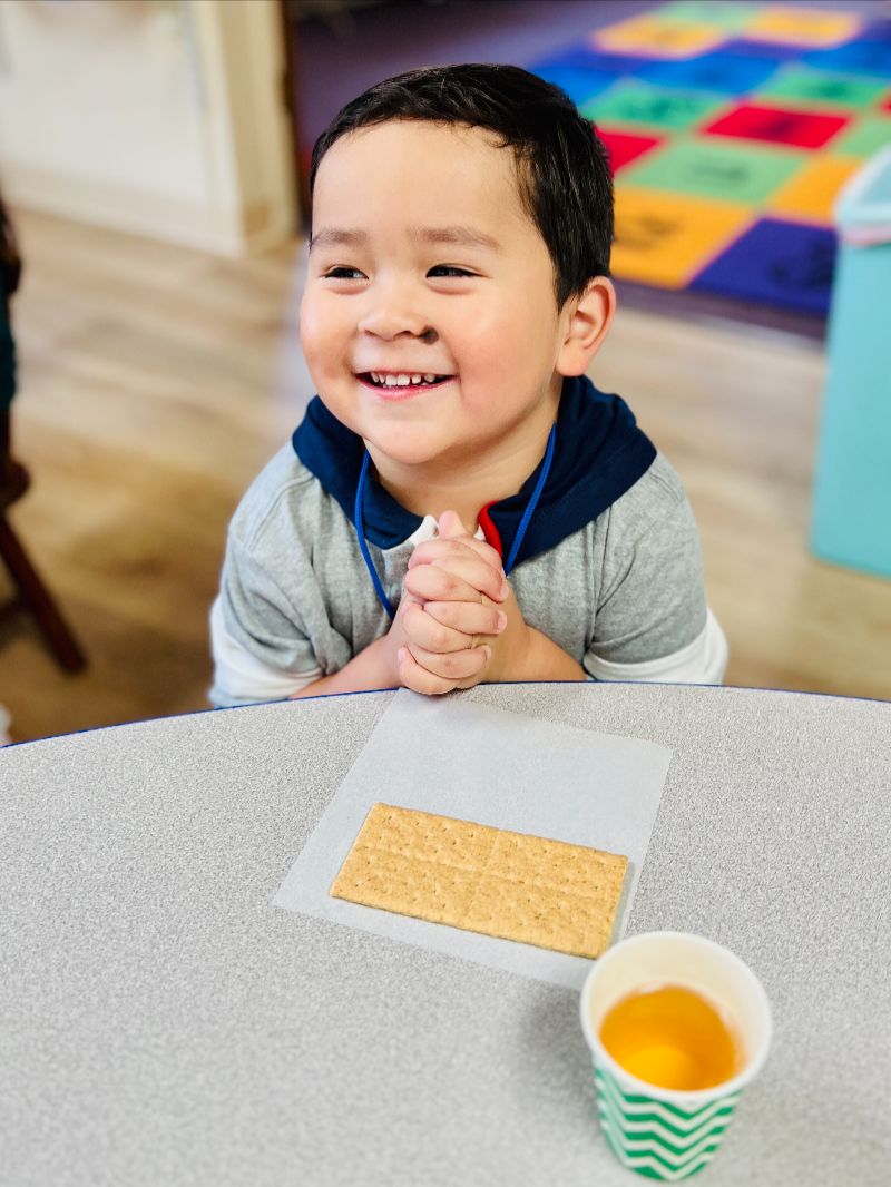 Happy preschool child during snack time at a daycare in Puyallup WA, showing a caring and joyful childcare environment.