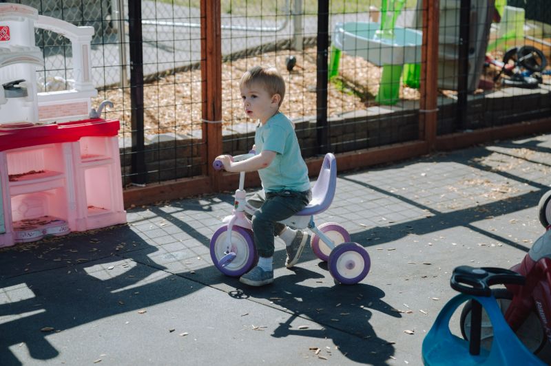 Toddler riding a tricycle outdoors at Lil’ Patriots Academy, highlighting the toddler program Puyallup with play-based learning activities.