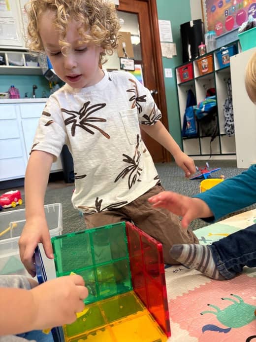 Child building with colorful blocks at Lil’ Patriots Academy STEM preschool program, supporting problem-solving and pre-k learning.
