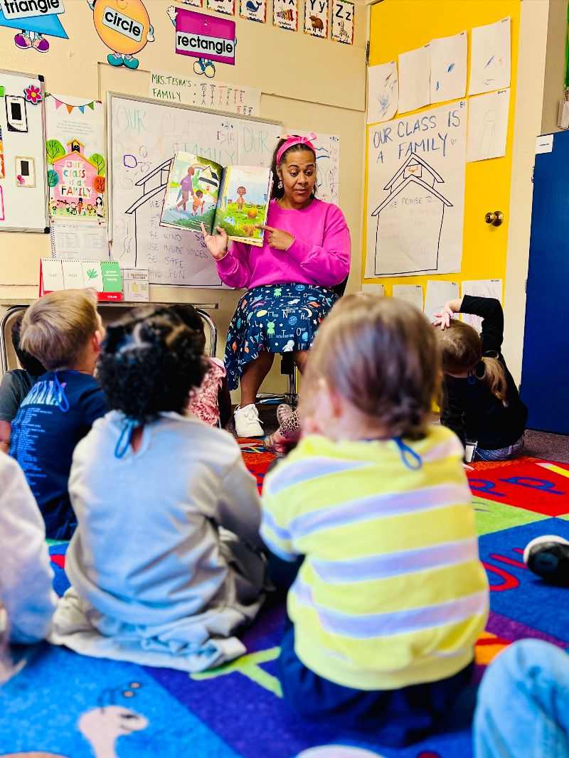 Teacher reading a storybook to children during class at a Puyallup WA daycare, encouraging literacy and engagement in early learning.